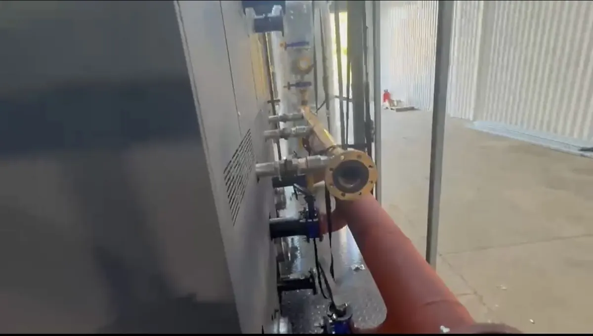 Close-up of pipework beside a grey boiler cabinet, showing an ochre-painted flanged connection, valves and ochre gas pipework