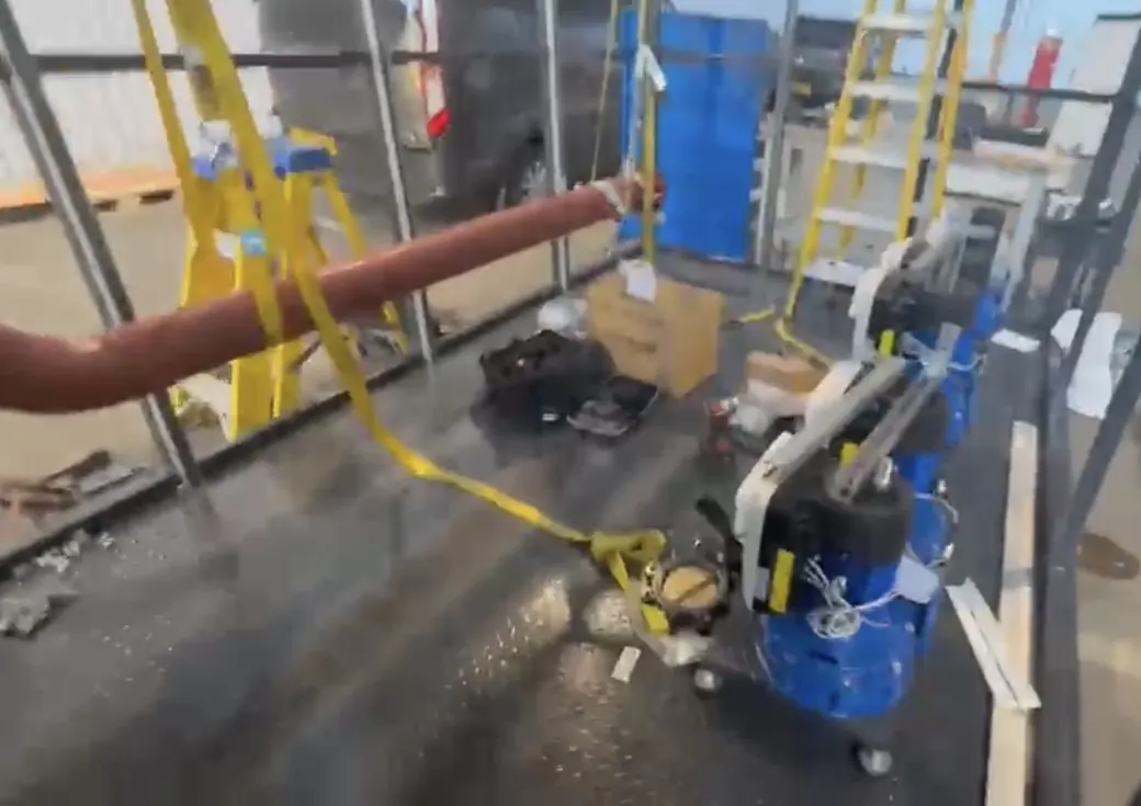 Inside the steel frame of the plant room during the workshop build, with blue pump sets on the floor and ladders behind